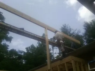 Carpenter setting a ridge beam over a new addition frame — Ice Dam Removal by Roofing Brothers in Balko