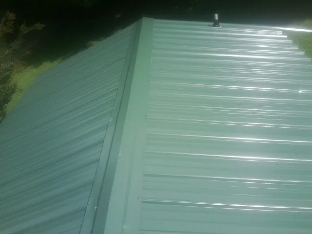 New green metal panels meeting at the ridge of a roof — Flat Roof Repair work by our crew in Balko