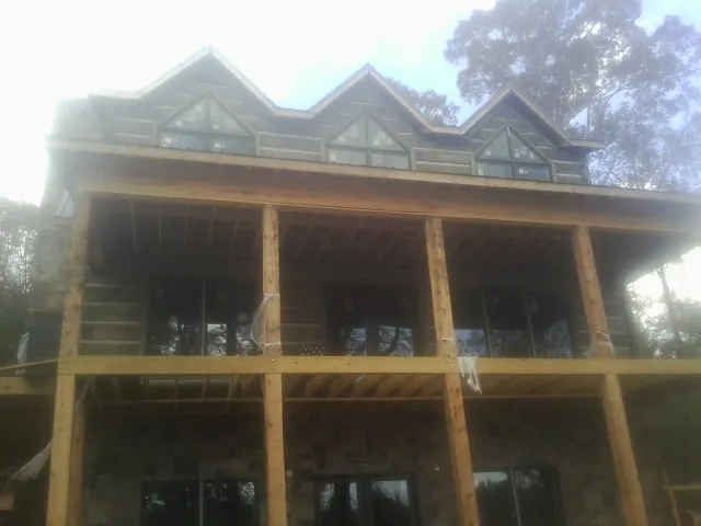 Dormers and porch framing on a large log home under construction — Roof Coating work by our crew in Balko
