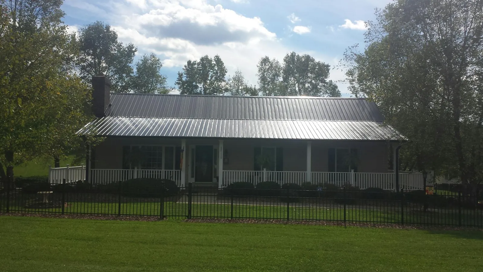 Gray metal roof on a brick ranch with a full width front porch — Gutter Guard Installation work by our crew in Balko