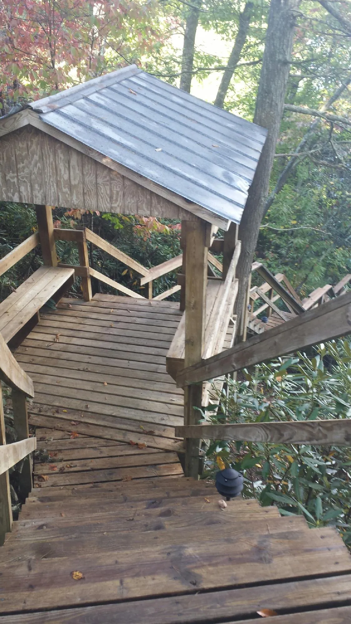 Metal roofed shelter over wooden steps on a wooded walkway — Skylight Repair & Installation work by our crew in Balko